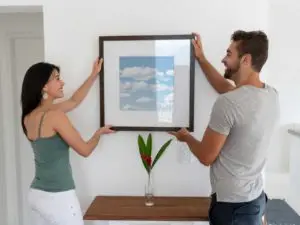 Crédences de cuisine personnalisées en Belgique couple accrochant un tableau en verre au mur